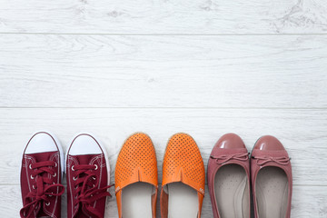 Flat lay fashion set: colored slippers shoes on white wooden background. Top view.