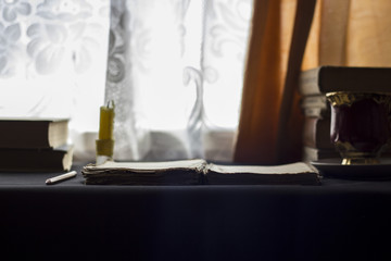 Open book on a table with a candle, day light