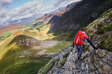 A hiker scrambling down towards High Snab Bank from the summit of Robinson in the Lake District,...