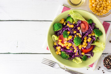Fresh vegetable salad on white wooden table.