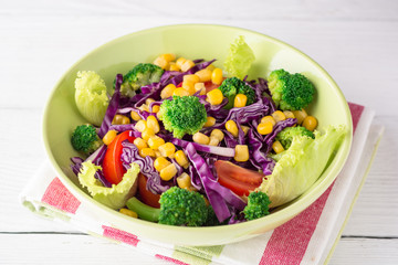 Fresh vegetable salad on white wooden table.