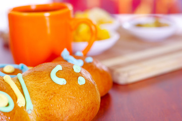 Elegant setup traditional tasty latin american guagua breads, colorful sugar decorations, orange cup with colada morada berry juice next to it, day of the dead concept