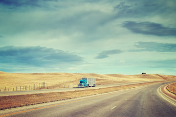 Color toned picture of American highway landscape with semi trailer truck