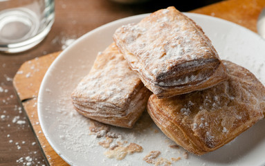 Few puff pastries in a white plate on a wooden table, closeup shot, selective focus