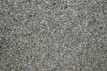 Background of concrete dark gray wall and multi-colored gravel with texture. Horizontal frame