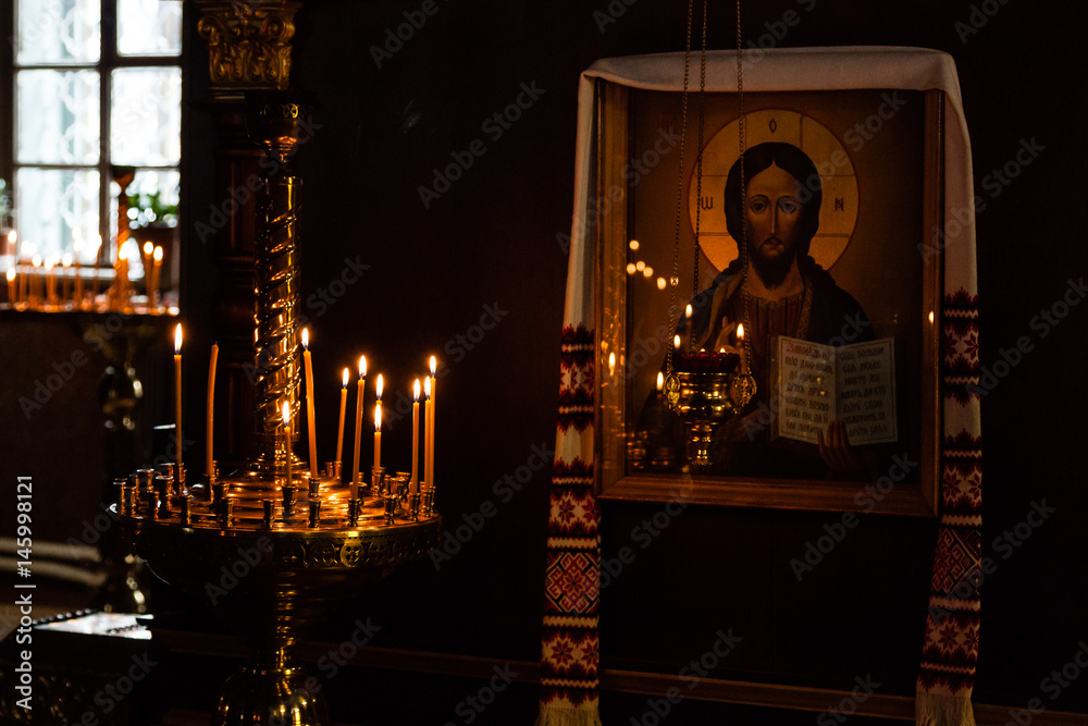 Wall mural Church candles burn in a candlestick against the backdrop of icons - Wall murals