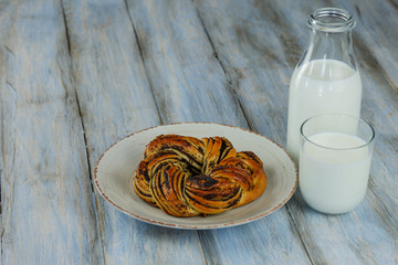 Breakfast. Baked pastry with poppy seeds on wooden background with glass and bottle of milk 