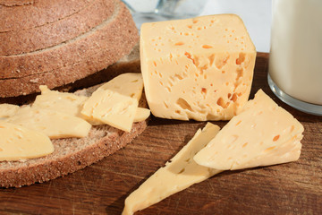 The cheese is cut pieces on a wooden board