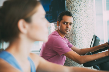 Serious young man and women cycling in gym