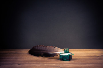Vintage old quill pen, inkwell on wooden table. Retro style filtered photo