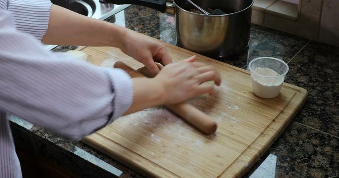 Female hands rolling fresh dough to make shells for meat pies 