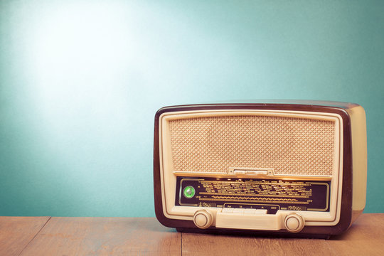 Old retro radio with green eye light on table front gradient background