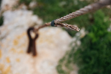 Rusty metal cable tied to a metal loop in the ground closeup blurred.