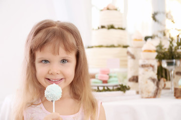 Cute little girl with tasty cake pop at party