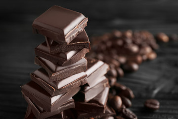 Chopped chocolate bars with coffee beans on table, closeup