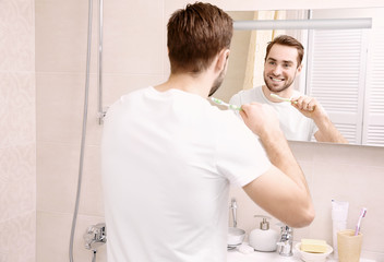 Obraz premium Handsome man brushing teeth in bathroom