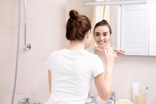 Beautiful woman brushing teeth in bathroom