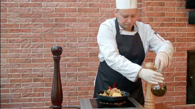 Chef finishing the dish, putting oil to a plate