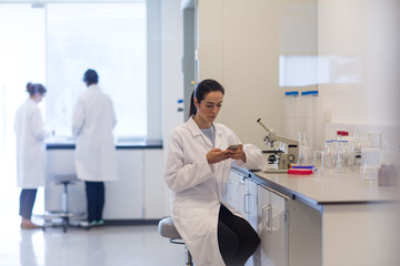Female scientist using smartphone in laboratory
