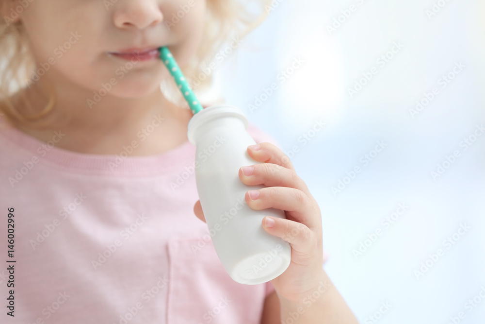 Poster cute little girl drinking yogurt at home, closeup