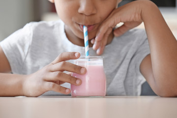Obraz na płótnie Canvas Cute African American boy drinking yogurt at home, closeup