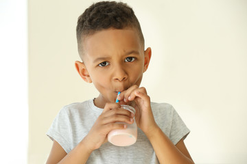 Cute African American boy drinking yogurt at home