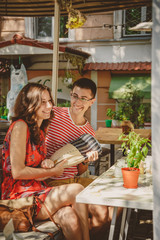 Young beautiful happy loving couple sitting at street open-air cafe, having fun with pillow. Beginning of love story. Relationship love, lifestyle concept. Couple in love on a date.