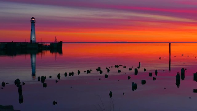 Scenic Wawatam Lighthouse in colorful predawn twilight, reflected in tranquil waters. Saint Ignace, Upper Michigan, seamless loop.