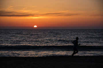Fototapeta premium Jogger at the beach in front of a colourful sunset