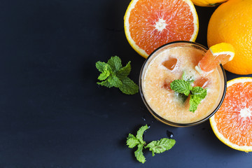 Fresh orange juice, mint and ice on dark background, top view