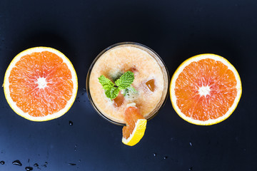 Fresh orange juice, mint and ice on dark background, top view