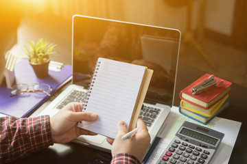 business, education and people concept - male hands with with note book, pencil and analysis with calculator,Skill improvement,The notebook page is open on the  desk table with laptop and supplies