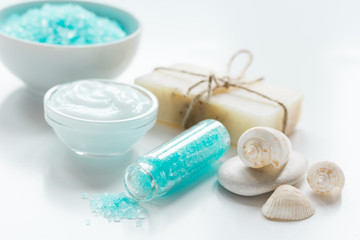 Obraz na płótnie Canvas blue bath salt, body cream and shells for spa on white table background