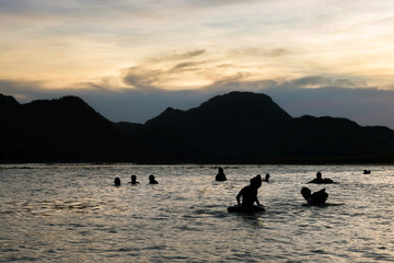 Silhouette , blurry , art tone of fresh water lake and mountain with people playing water on evening sky background