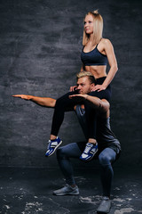 Fototapeta na wymiar Sporty male doing squats with slim fit female on his shoulders.