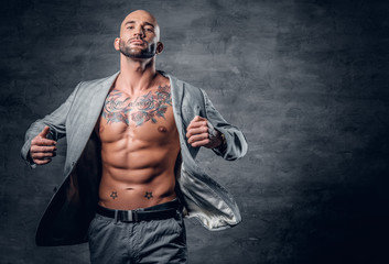 Fototapeta na wymiar Shaved head tattooed male dressed in a grey jacket on a naked torso.