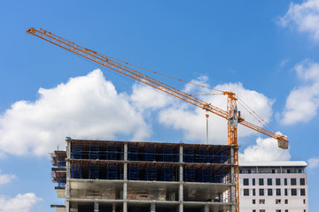 Crane lifting concrete mixer container against blue sky