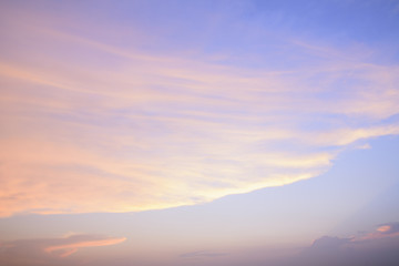 Soft pastel-colored clouds blend with the sky as the sun sets, creating a serene and peaceful atmosphere.