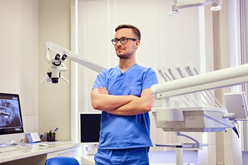Naklejka na ściany i meble Male dentist in a room with medical equipment on background.
