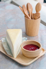 Crepe cake with strawberry sauce in wooden tray on the table