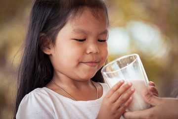 Asian little girl try to drink a milk from glass she don't like it