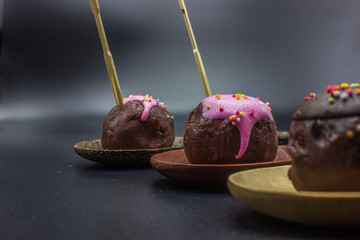 Close up sweet chocolate and handmade cake ball in the wooden ladles on black background.