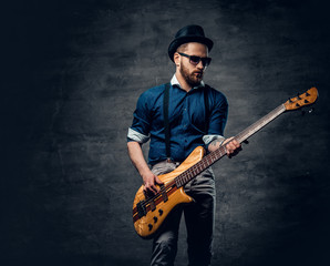 Obraz premium Studio portrait of the hipster bass player dressed in cylinder hat.