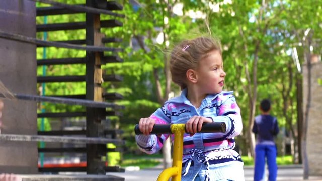 Two little kids sitting on a seesaw in the playground. Slow motion