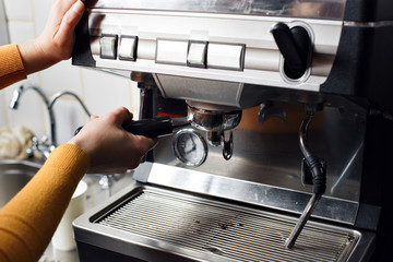 small business, people and service concept - woman or waiter in apron with holder and tamper preparing coffee at coffee shop