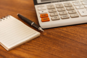 Blank notebook with pen and calculator on wooden table, business concept