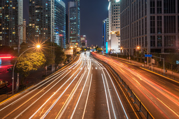 Fototapeta na wymiar light trails on city street with cityscape at night in China.