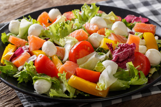 Fresh salad with salted salmon, mozzarella cheese and vegetables close-up. horizontal