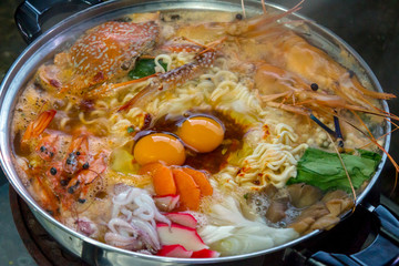 Seafood set of Sukiyaki, Shabu with noodle and vegetable in the pot on wooden table