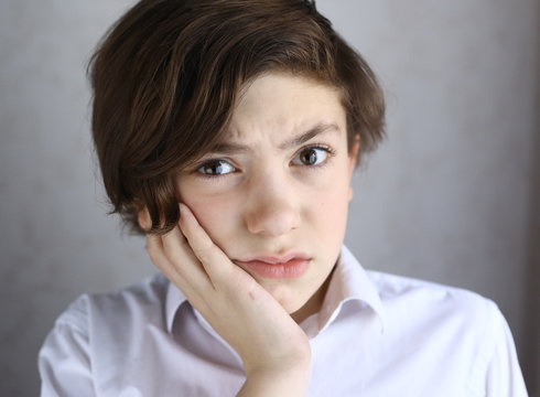 teen boy with toothache holding his cheek